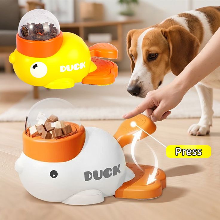 A dog interacting with a duck-shaped dog treat dispensing toy as a person presses the pedal to release treats.